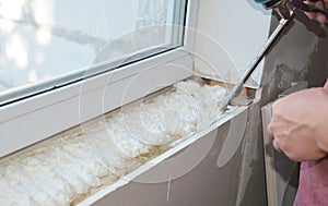 Installing window sill with caulking gun foam. House window installation indoors