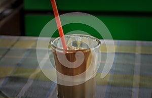 Instant coffe in a glass with a red straw