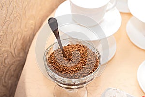 Instant coffee in a glass bowl on a background of white coffee cups