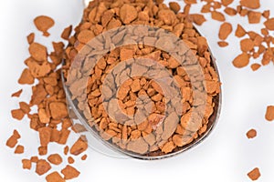 Instant coffee granules in spoon, close-up in selective focus