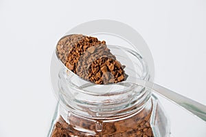 Instant coffee granules in a spoon, macro, on white background