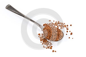 Instant coffee granules in spoon and beside on white surface