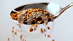 Instant coffee pieces falling from spoon in slow motion on white background