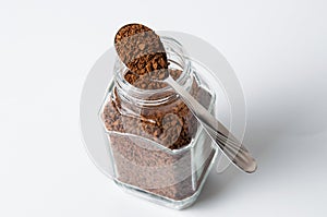Instant coffee in pot and a spoon on a white background