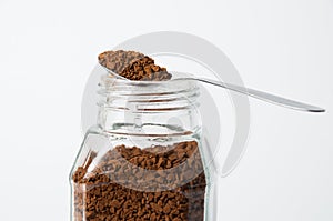 Instant coffee in spoon and a can on a white background, side view