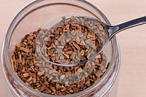 Instant coffee in a spoon.Close up.Glass transparent jar with coffee granules. View from above