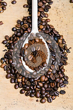Instant coffee in spoon on coffee beans