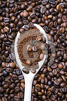 Instant coffee in spoon on coffee beans