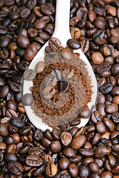 Instant coffee in spoon on coffee beans