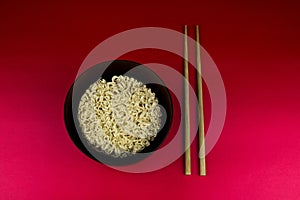 Instant Noodle Block in a Wooden Bowl with Chopsticks on a Red Table Top
