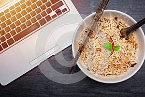 Instant noodle with computer laptop for low cost cheap eat and unhealthy high carbohydrate food concept