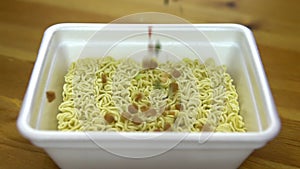 In the instant noodles backfilled spices. Ramen in a special plastic plate. Slow motion