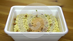 In the instant noodles backfilled spices. Ramen in a special plastic plate. Slow motion