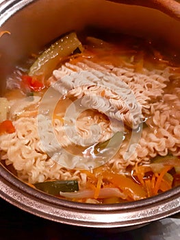 Instant noodles dipped in a pot with previously boiled various vegetables