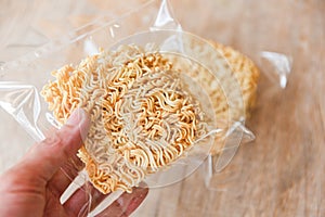 Instant noodles in package in hand dry food non perishable storage goods in kitchen home or for donations