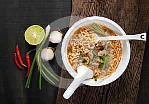 Instant noodles in plastic bowl and vegetable side dishes on woo