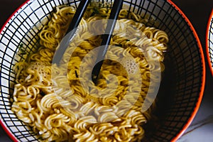 Instant pasta, Japanese and Chinese noodles. Ramen type soup in a plate with chopsticks, junk fast food. Quick-cooking pasta