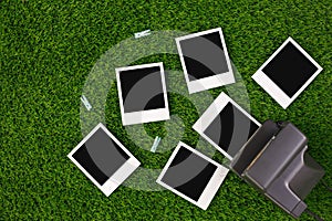 Instant photo frames and a camera on a background of lawn grass. Concept of preservation of memories. Flat lay