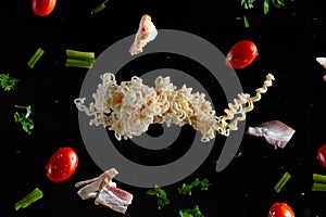 Instant vermicelli, fresh bacon and cherry tomatoes, parsley and green onions with water drops, frozen in motion