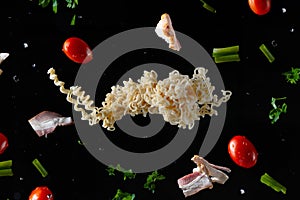 Instant vermicelli, fresh bacon and cherry tomatoes, parsley and green onions with water drops, frozen in motion