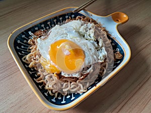 instantly fried noddle with a fried egg with wooden background photo