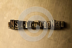 INSTITUTIONAL - close-up of grungy vintage typeset word on metal backdrop