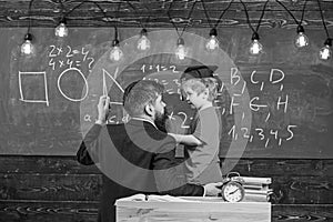 Instructive conversation concept. Teacher with beard, father teaches little son in classroom, chalkboard on background