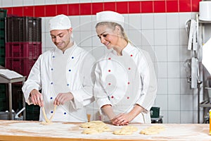 Instructor and apprentice in bakery making pretzels