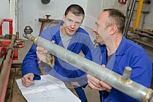 Instructor and apprentice looking at pipe