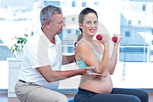 Instructor assisting cheerful pregnant woman