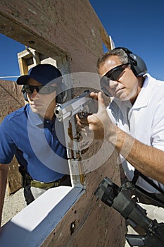 Instructor Assisting Man With Hand Gun