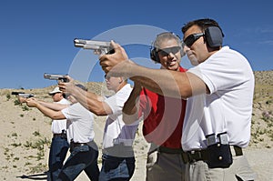 Instructor Assisting Officers With Hand Guns At Firing Range