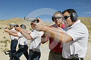 Instructor Assisting Officers With Hand Guns At Firing Range