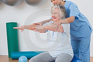 Instructor assisting senior woman to exercise