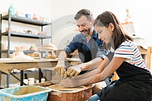 Instructor Assisting Student In Making Pottery