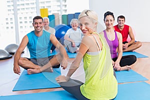 Instructor with class practicing yoga in fitness studio