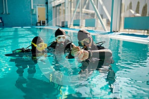 Instructor and divers in aqualungs, dive lesson