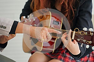Instructor finger pointing to student guitar to teach chords guitar in music academy