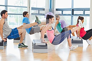 Instructor with fitness class performing step aerobics exercise