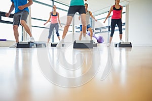 Instructor with fitness class performing step aerobics exercise