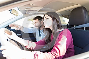 Instructor Gesturing While Teaching Car Driving To Student