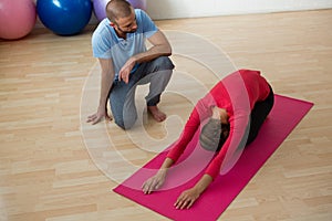 Instructor guiding student in doing child pose at yoga studio