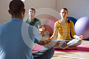 Instructor guiding students in meditation at health club