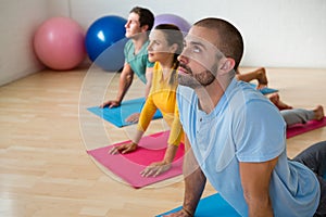 Instructor guiding students in practicing cobra pose at yoga studio