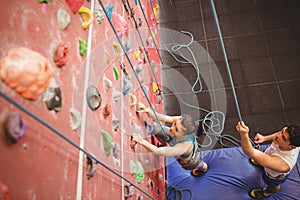 Instructor guiding woman on rock climbing wall