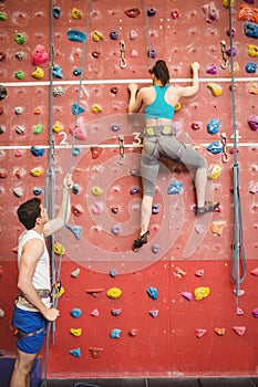 Instructor guiding woman on rock climbing wall