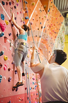 Instructor guiding woman on rock climbing wall