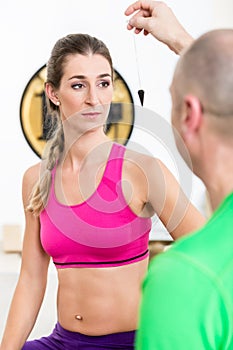 Instructor hypnotizing woman with pendulum tool