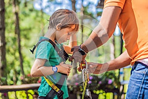 Instructor puts on the child climbing equipment for safe passage on the rope park