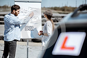 Instructor showing traffic shemes to a female student outdooors